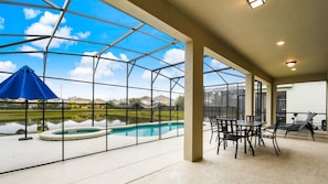 A covered outdoor area with a pool, chairs, and a view through a large window. - Veranda Palms Lakeview 6br Villa Pool Spa, Disney (Kissimmee)