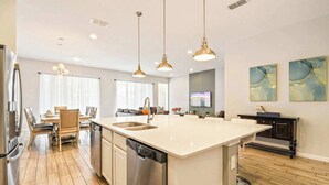 A modern kitchen with a central island, stainless steel appliances, and pendant lighting. - Spacious 12-bed Villa With Pool & Resort Amenities (Kissimmee)
