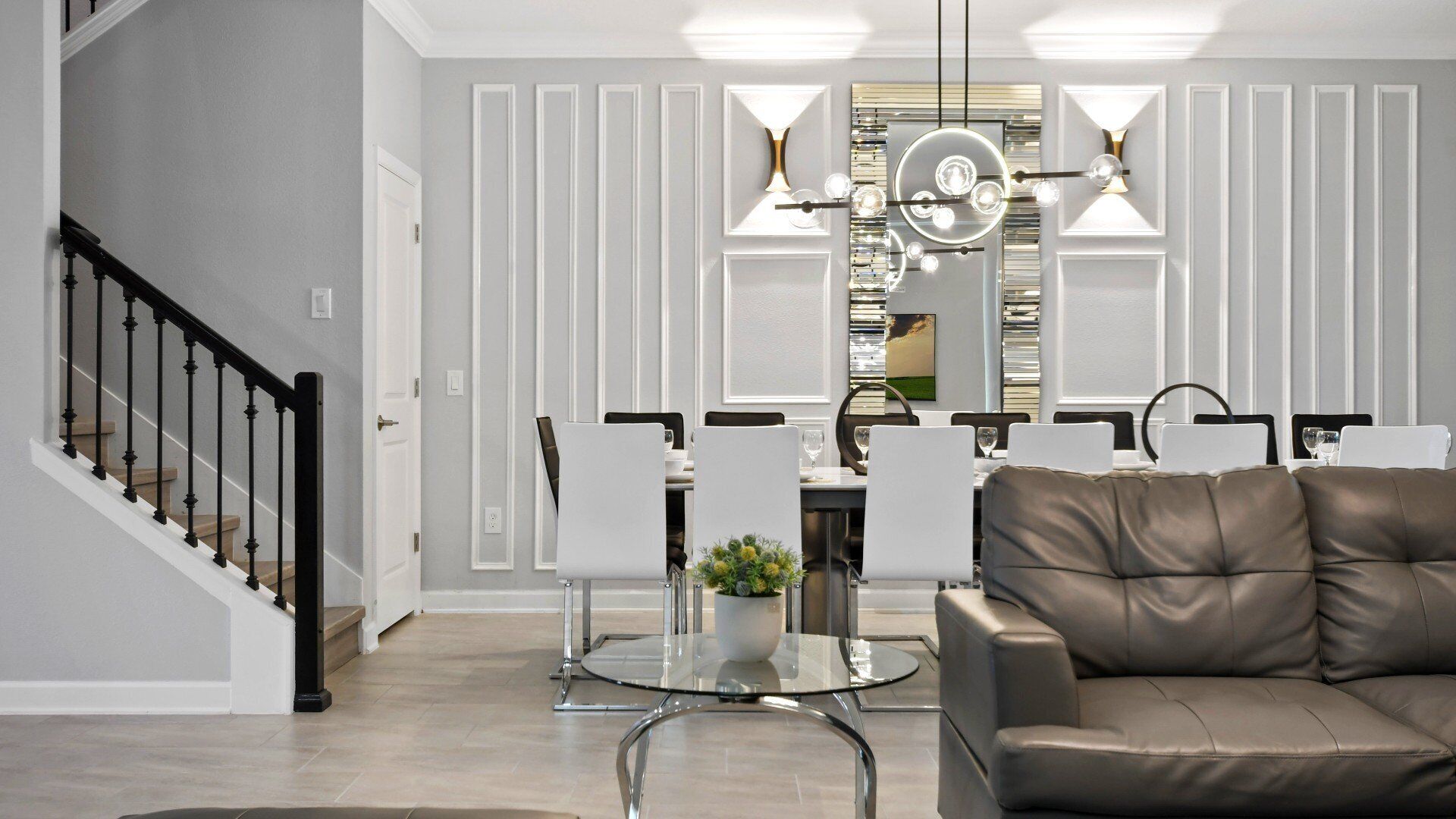 A modern dining area with a glass table, chairs, and a leather sofa.
