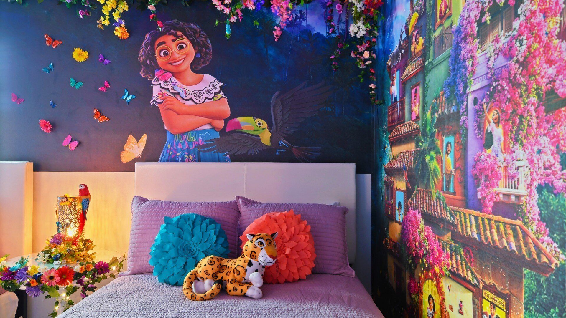 A bedroom with a mural of a character, a bed with colorful pillows, and a decorative wall.