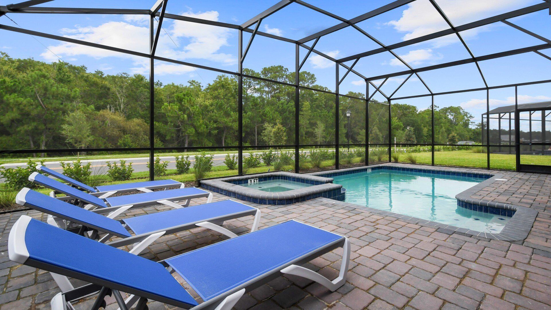 A covered outdoor swimming pool with lounge chairs and a hot tub.