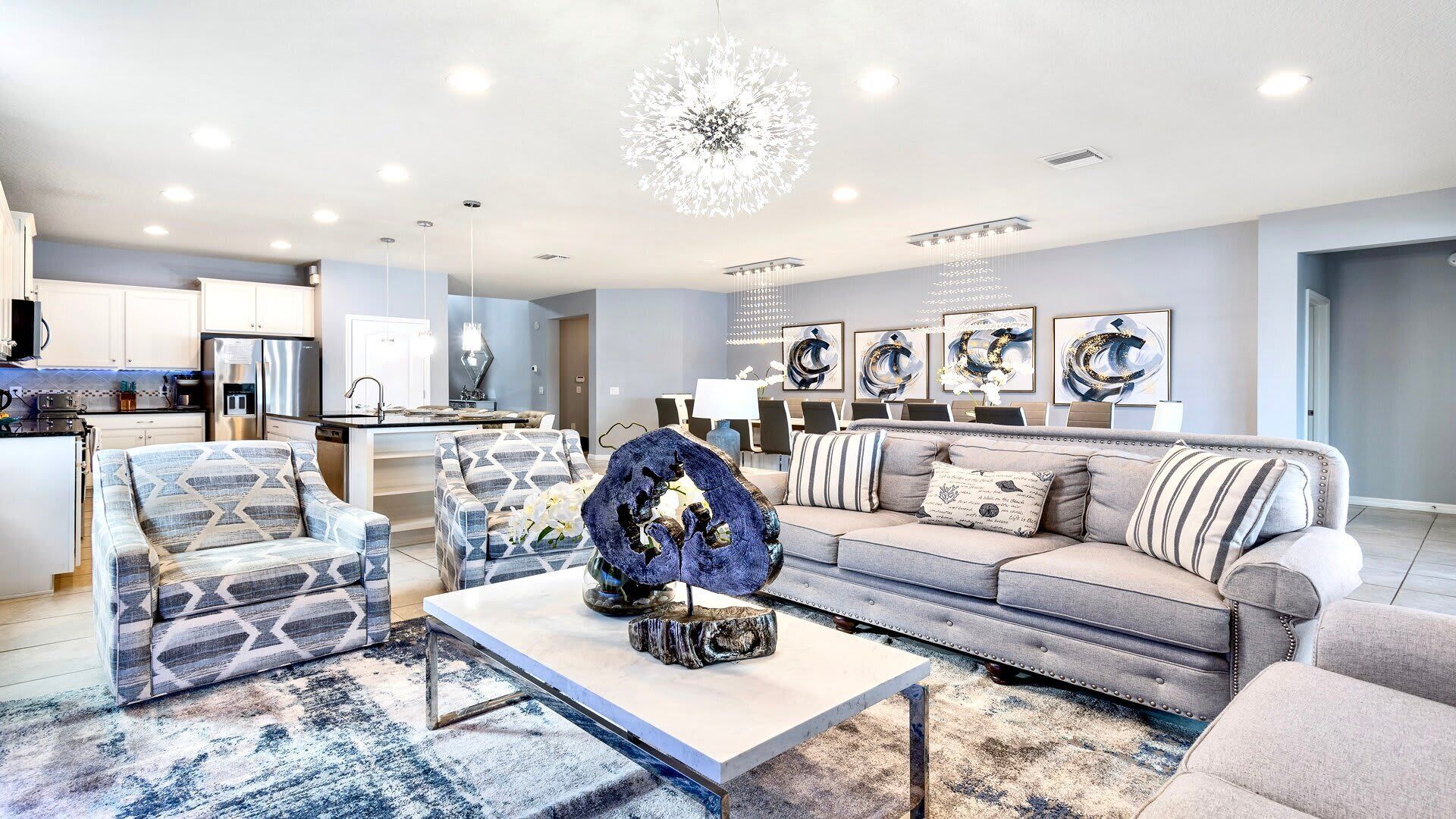 Een moderne woonkamer met een bank, fauteuils, een salontafel en een decoratief middelpunt.