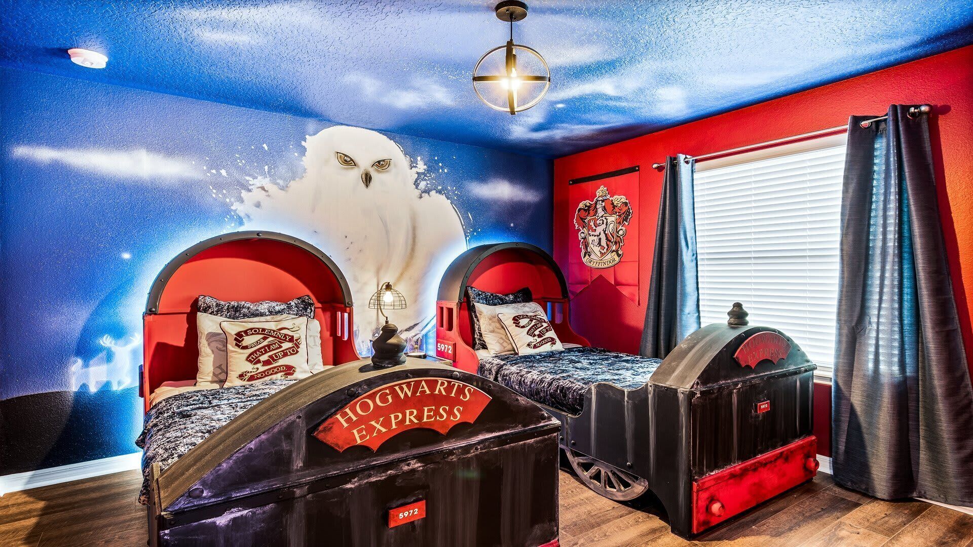 Une chambre avec deux lits, une fresque au plafond, les armoiries de Gryffondor et une pancarte sur laquelle on peut lire : « Hogwarts Express ».
