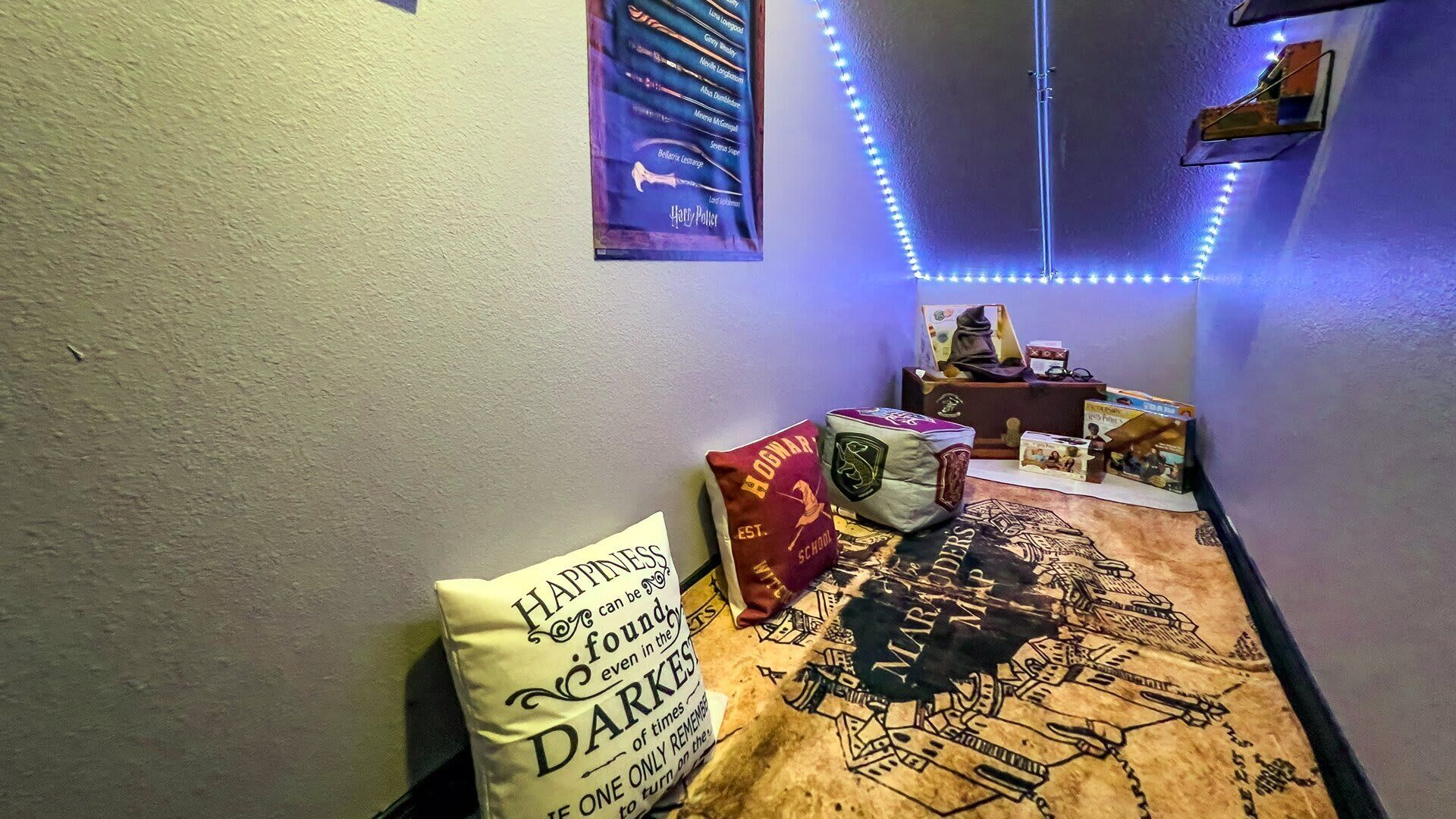 A hallway with a Harry Potter themed carpet, a pillow with a quote, and a poster on the wall.