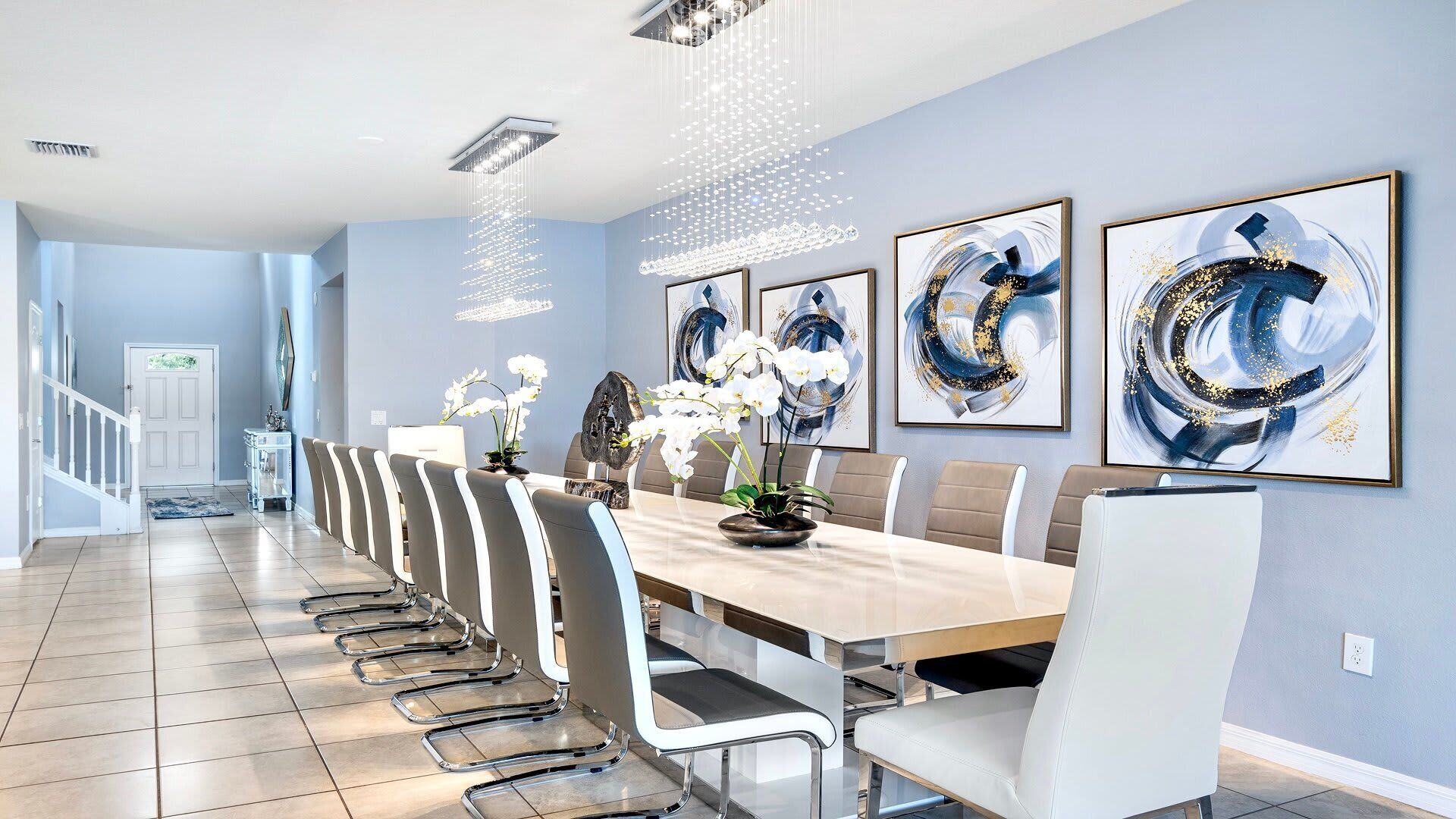A modern dining room with a long table, white chairs, and abstract art on the walls.