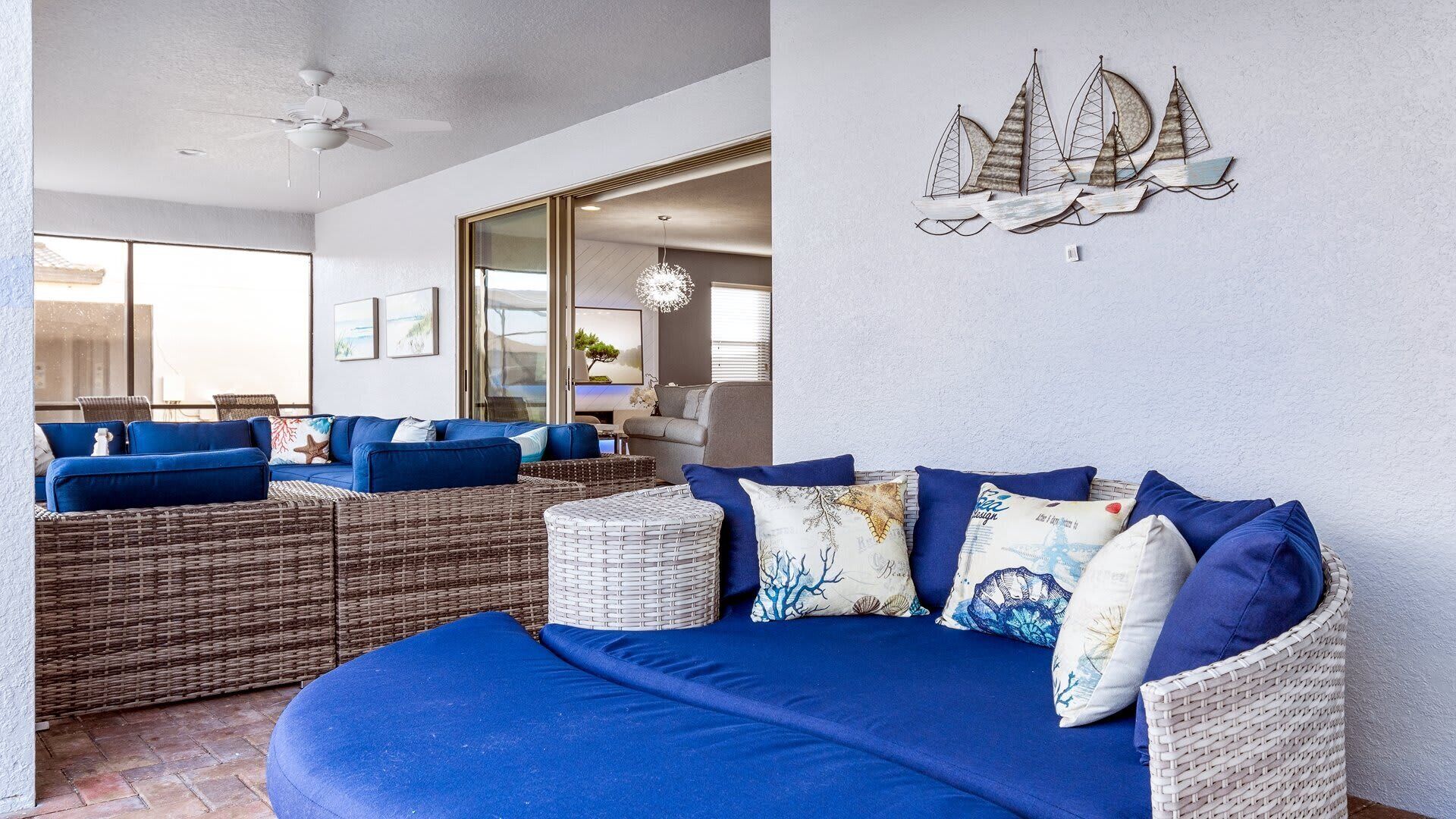 A living room with a blue sofa, wicker furniture, and a wall-mounted sailboat decoration.