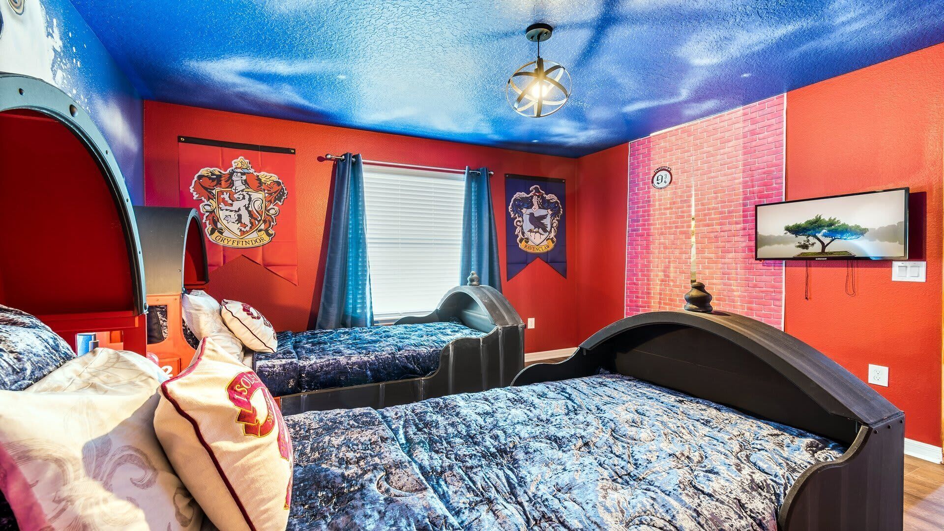 A room with two beds, a red brick wall, and a ceiling painted to resemble a starry sky.