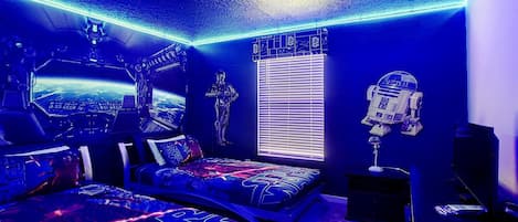 Ein Schlafzimmer im Stil von Star Wars mit einem Bett, einem Fenster und Star-Wars-Sammlerstücken.