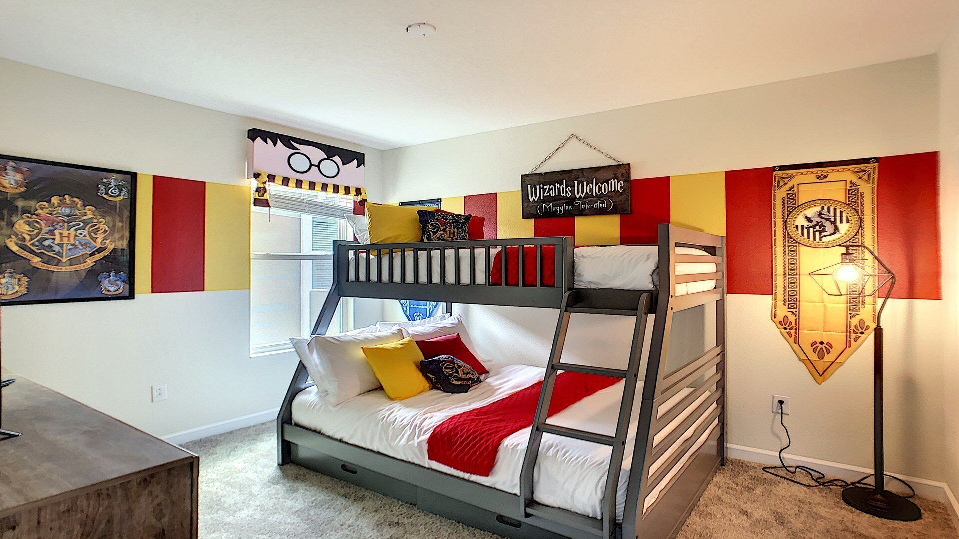Habitación con literas decorada con motivos de Hogwarts, un cartel que dice 'Magos bienvenidos (Muggles tolerados)' y una lámpara con sombrero de mago.
