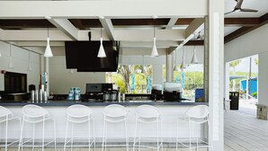 A modern kitchen with a bar area, white bar stools, and pendant lighting. - Storey Lake 5br Family Townhome w Pool Near Disney (Kissimmee)