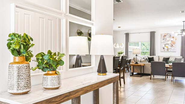 A modern living room with a white fireplace, a dining area with a table and chairs, and a sofa. - Storey Lake 5br Family Townhome w Pool Near Disney (Kissimmee)