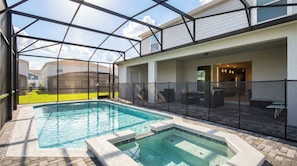 Una piscina con cerramiento de vidrio, un jacuzzi y mobiliario exterior.