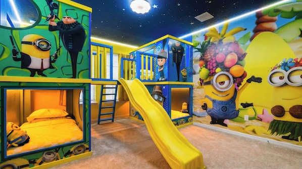 A children's play area with colorful play structures, a slide, and Minion-themed decorations.