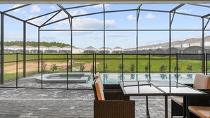 A covered outdoor area with a glass enclosure, a pool table, and outdoor seating. - Luxury Family Escape at Windsor Island Orlando (Davenport)