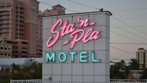 Eine Neonreklame für das Motel 'Sta'n-Pla' mit einem gitterartigen Hintergrund.