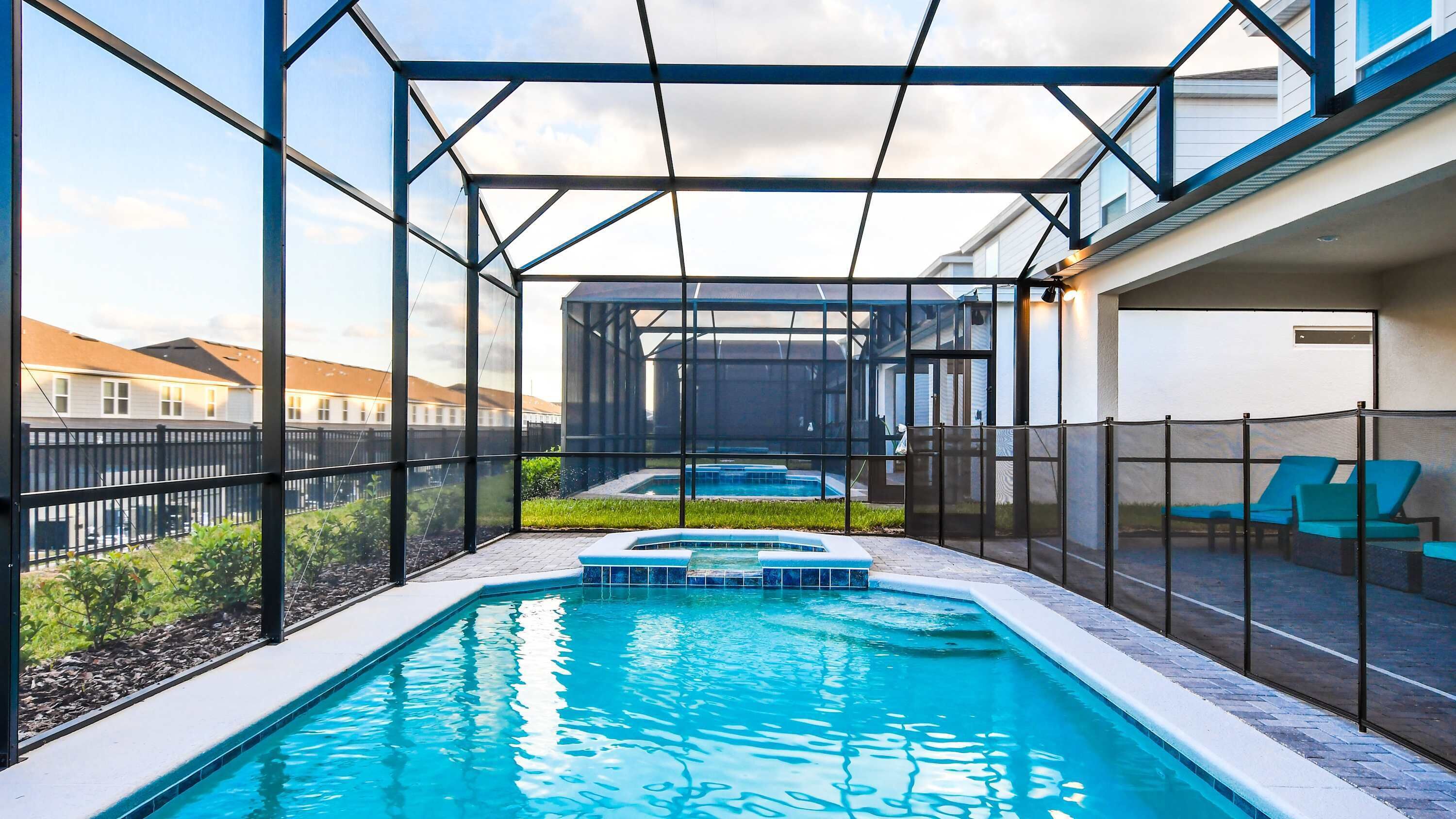 Una piscina interior con cerramiento de vidrio, un jacuzzi y sillones de descanso.