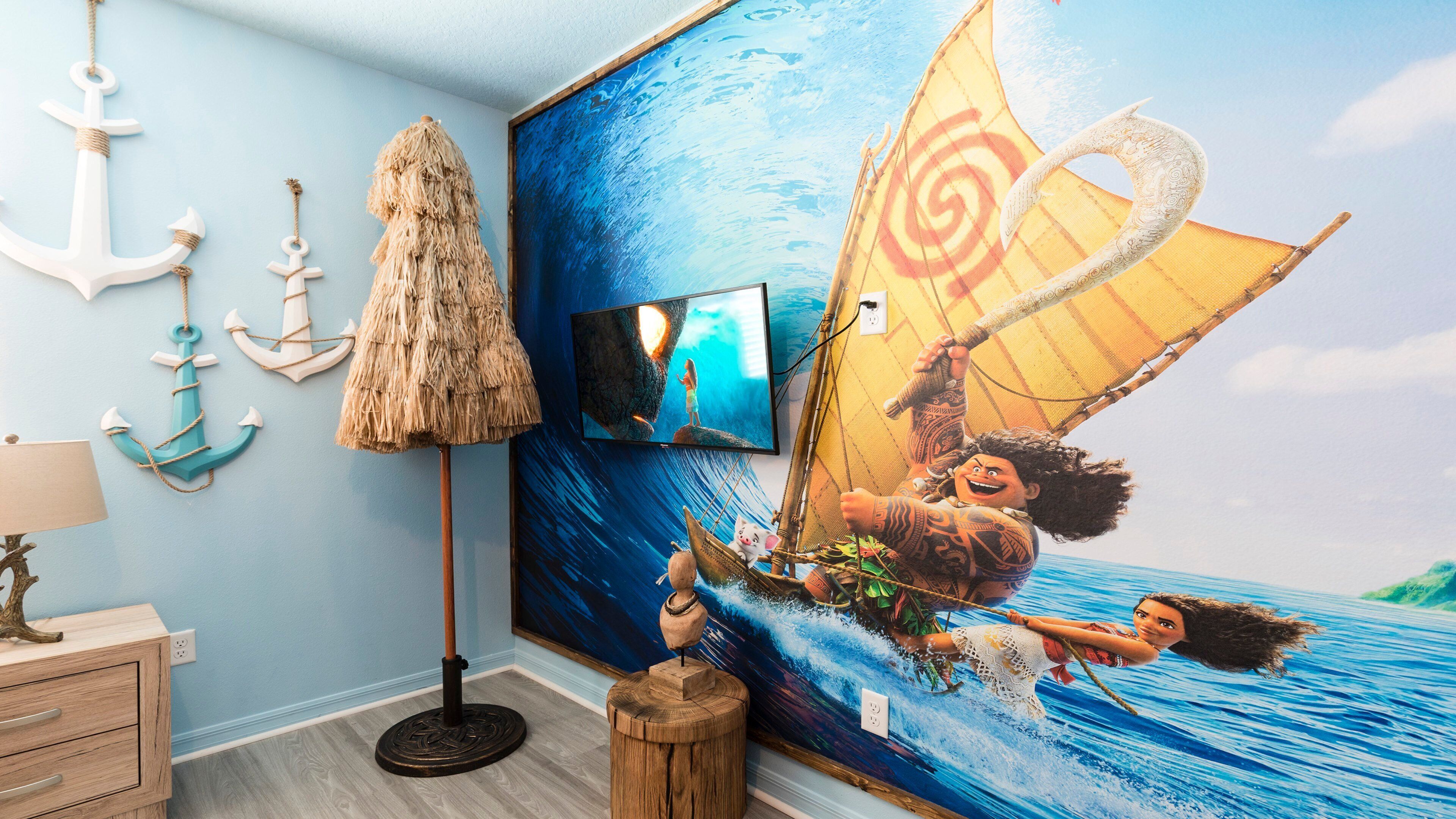 Een kamer met een muurschildering van een personage op een boot, een televisie en decoratieve ankers.