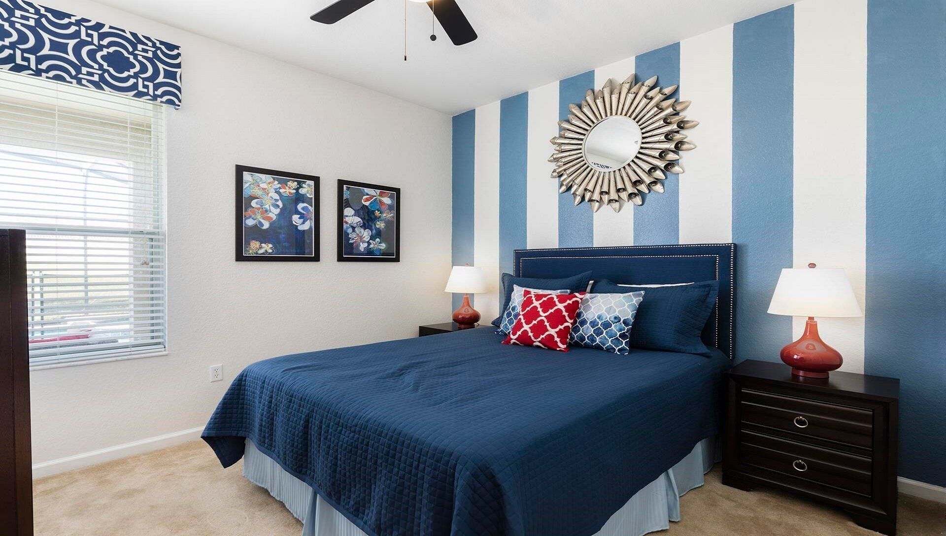 A bedroom with a bed, two nightstands, a mirror, and two framed pictures on the wall.