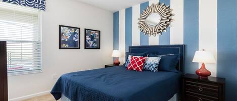 A bedroom with a bed, two nightstands, a mirror, and two framed pictures on the wall.