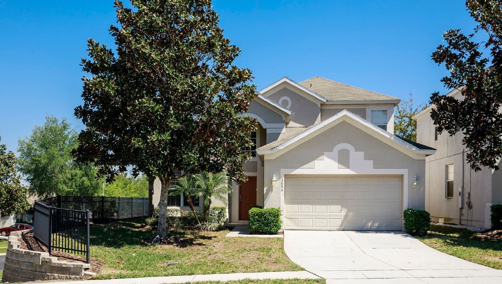 A single-story house with a garage, a front yard with a tree, and a sidewalk.