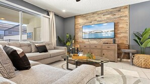 Ein modernes Wohnzimmer mit einer Couch, einem Couchtisch und einem an einer Holzwand montierten Fernseher.