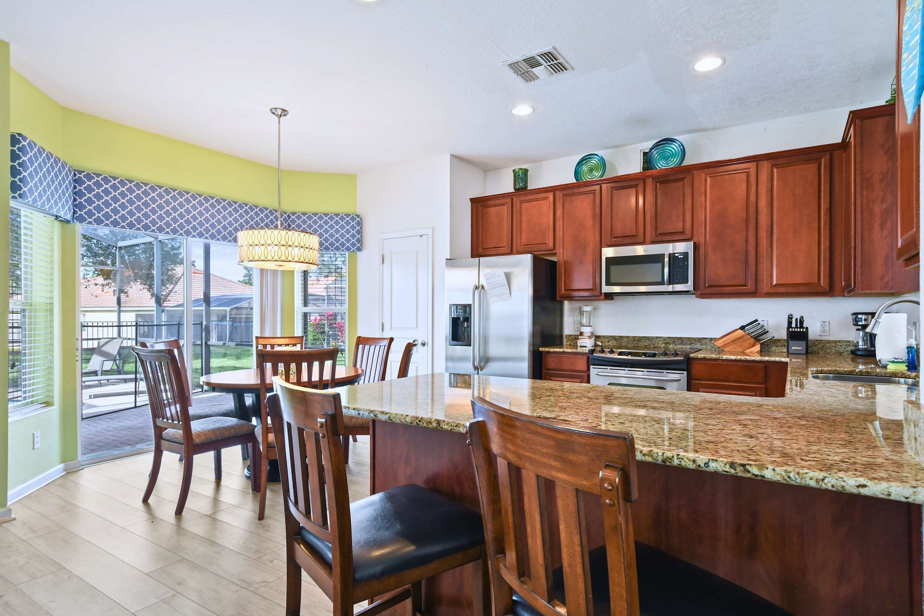 A modern kitchen with granite countertops, wooden cabinets, and stainless steel appliances.