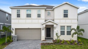 A two-story house with a garage, a front porch, and a well-maintained lawn. - Opulent Villa in Resort Near Theme Parks & Shops (Davenport)
