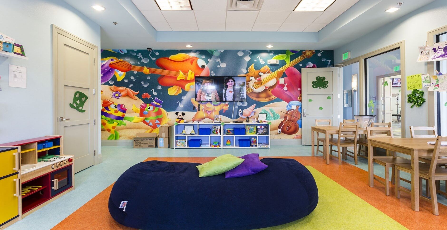 A kids' playroom with a colorful mural, a bean bag, and a play table.