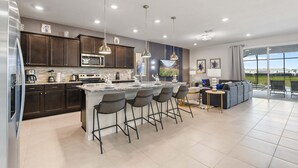 Una cocina moderna con armarios de madera oscura, una isla grande con taburetes de bar e iluminación colgante.
