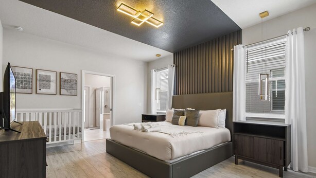 Un dormitorio moderno con una cama grande, un cabecero oscuro y suelo de madera.