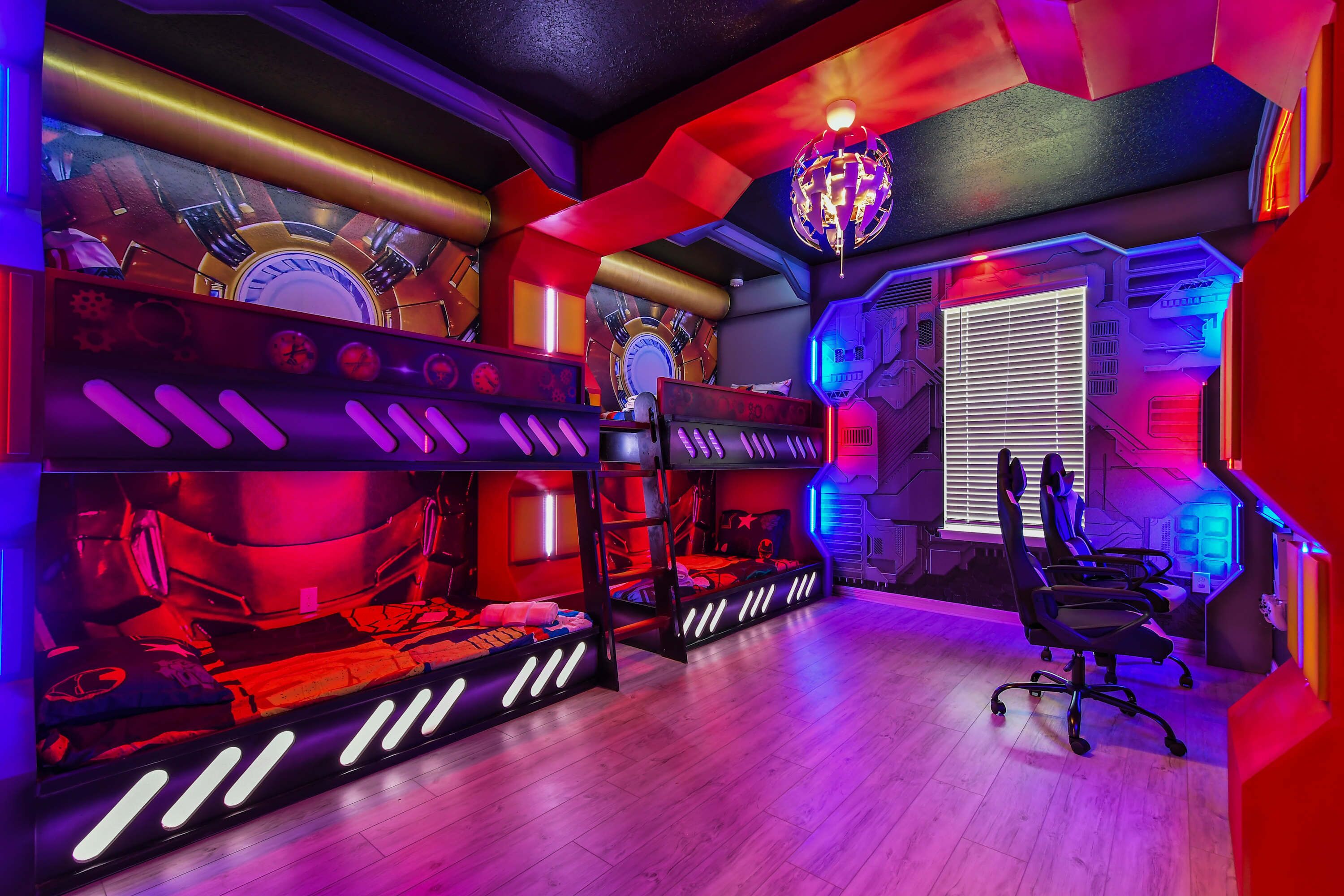 A room with bunk beds, a desk, and a gaming chair.