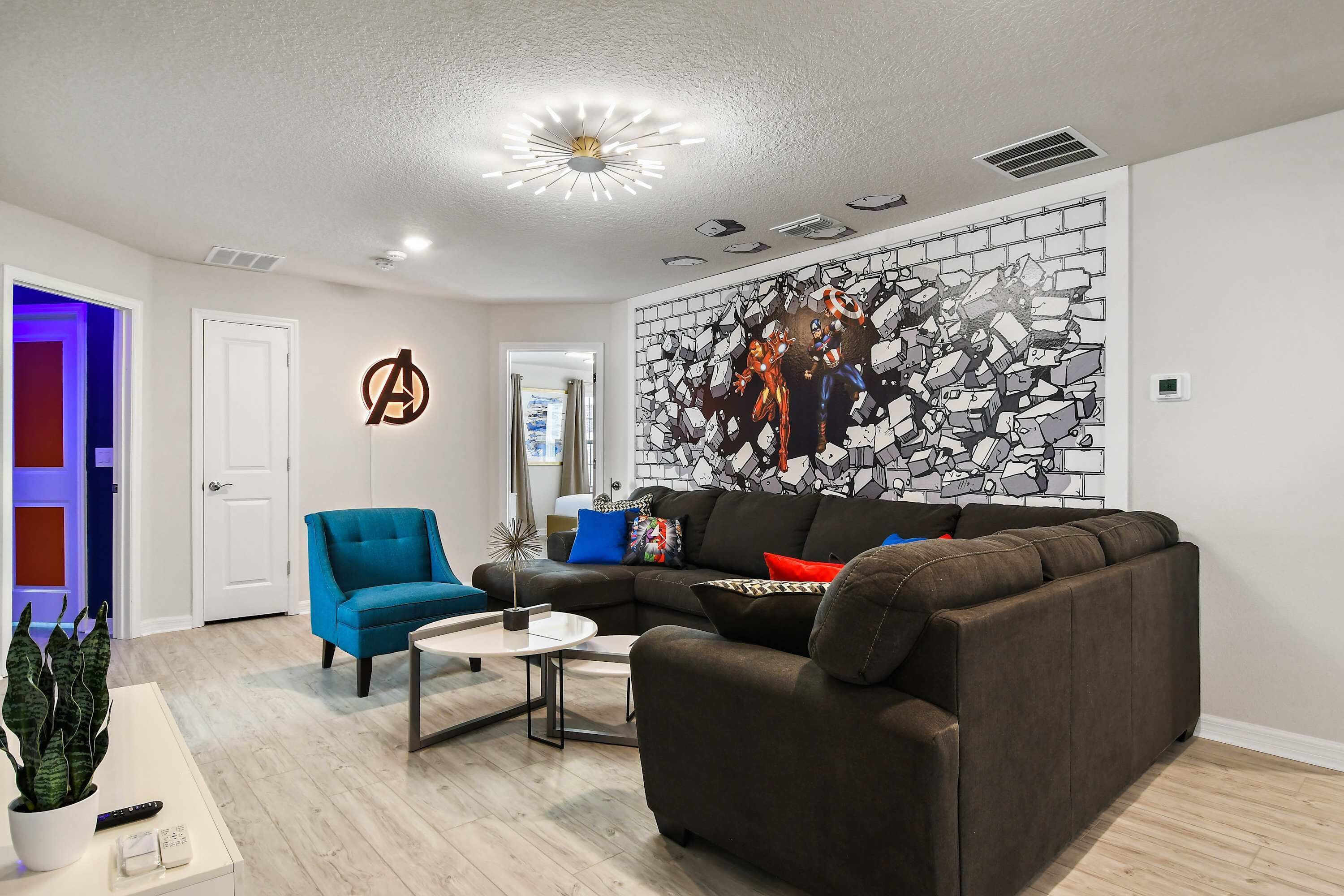 A modern living room with a sectional sofa, a blue armchair, a coffee table, and a wall mural.
