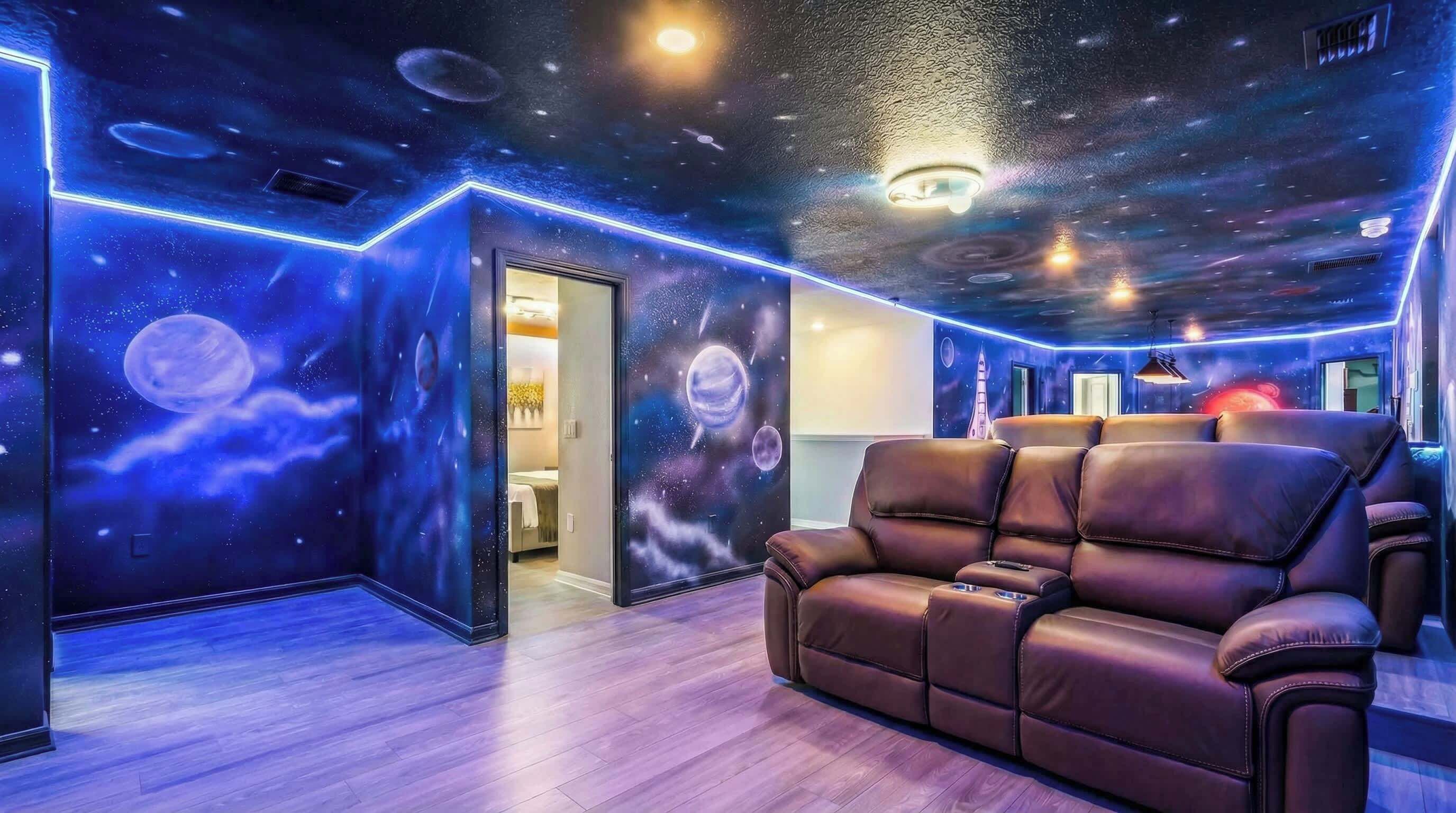 A room with a space-themed ceiling, a leather sofa, and a door leading to another room.