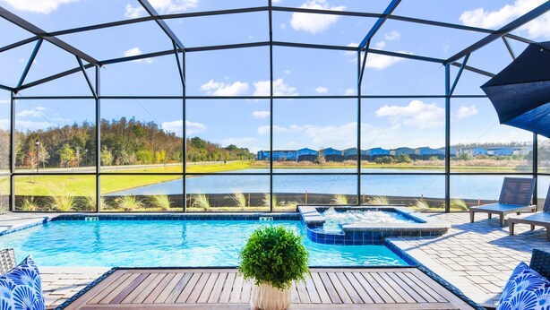 Un espace piscine offrant une vue sur un lac et des bâtiments en arrière-plan.
