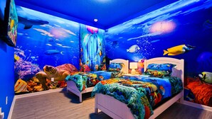 A bedroom with an aquarium wall, two beds, and a nightstand with a lamp. - Veranda Plams 9BR Villa Private Pool Spa 2570 (Kissimmee)