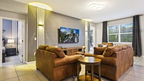 A modern living room with a sofa set, a coffee table, and a flat-screen TV mounted on the wall. - Veranda Plams 9BR Villa Private Pool Spa 2570 (Kissimmee)