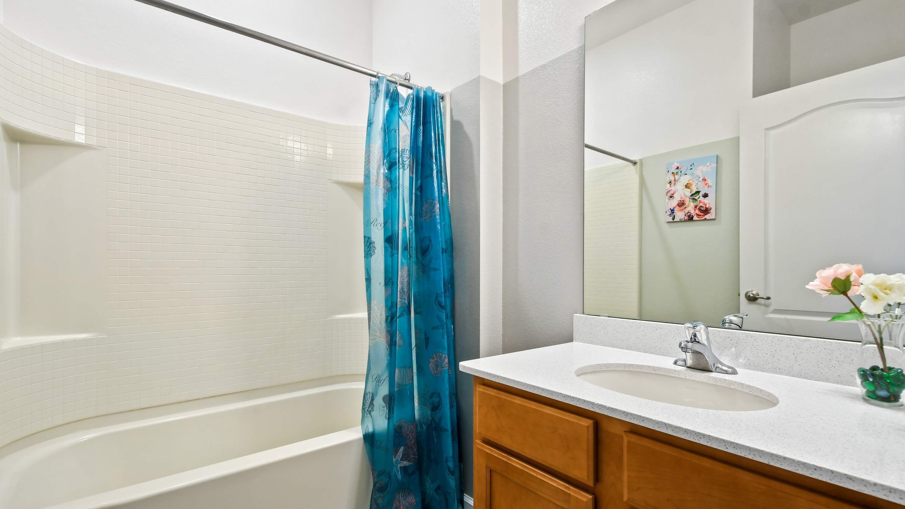 Une salle de bain avec une baignoire, un rideau de douche, un lavabo et un miroir.