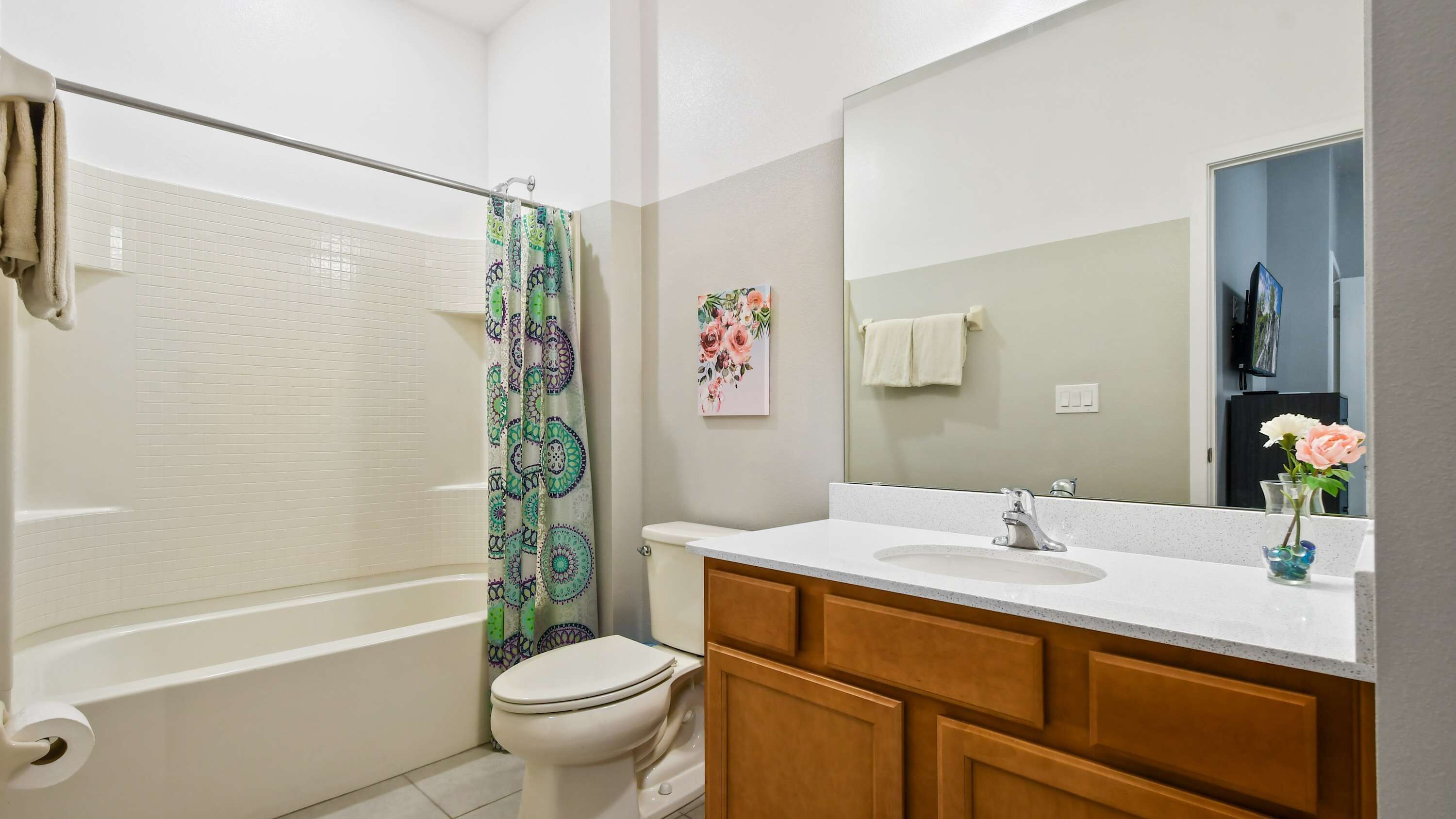 A bathroom with a shower, toilet, sink, and mirror.