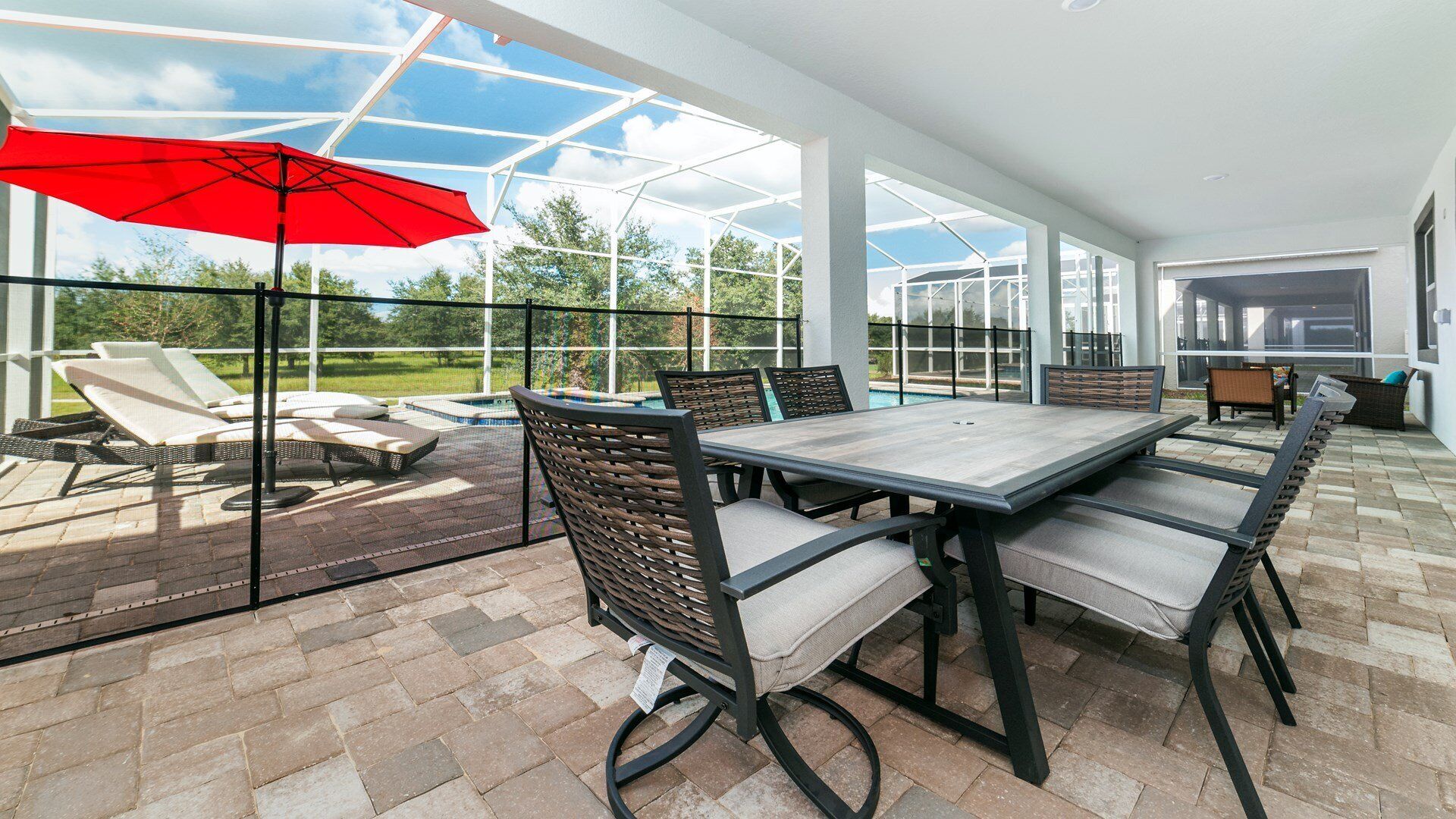 A covered patio with a pool, outdoor furniture, and a large umbrella.