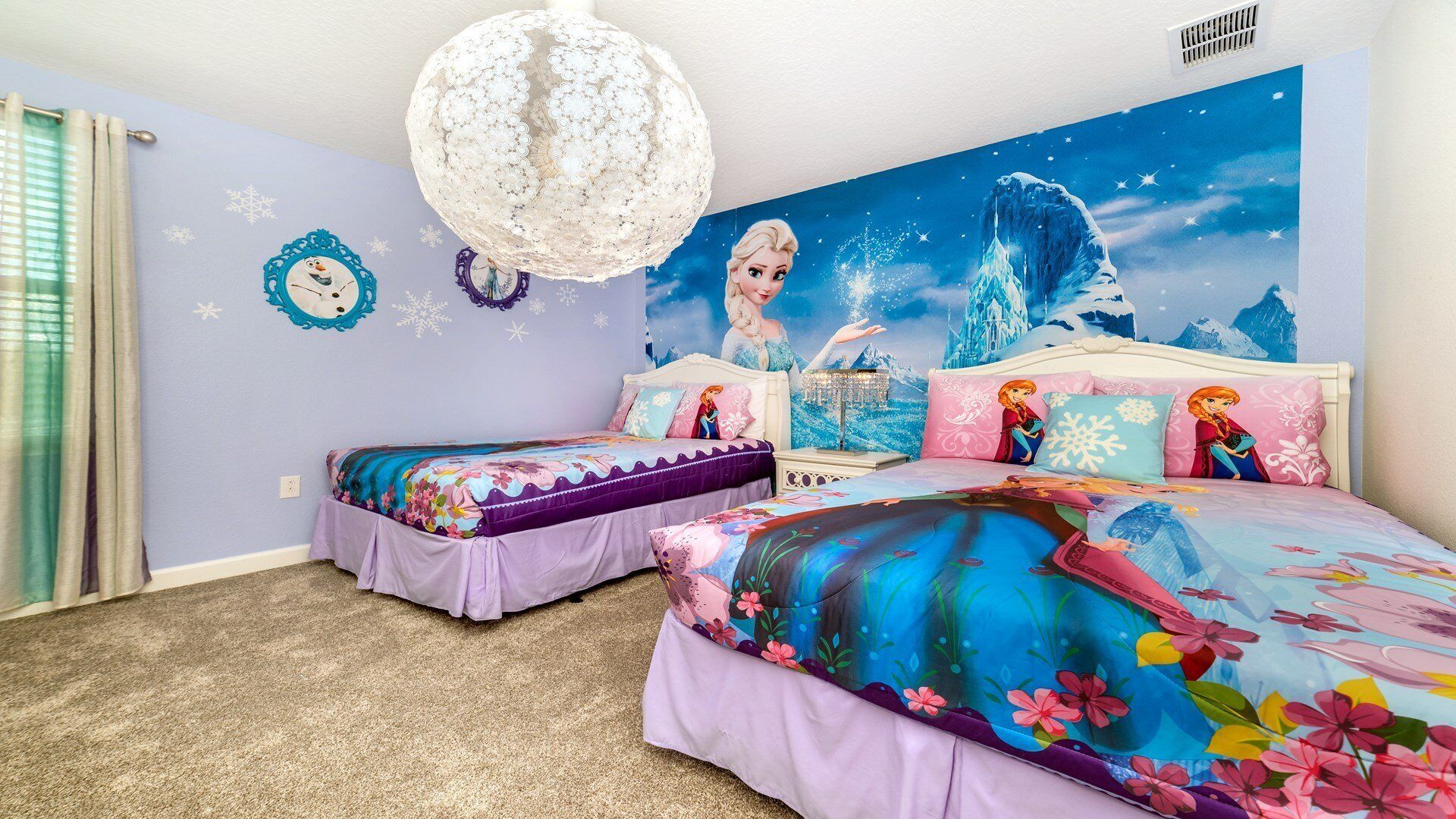 Ein Schlafzimmer mit zwei Betten, einer Chandelier und einem Wandbild mit Winterlandschaft.