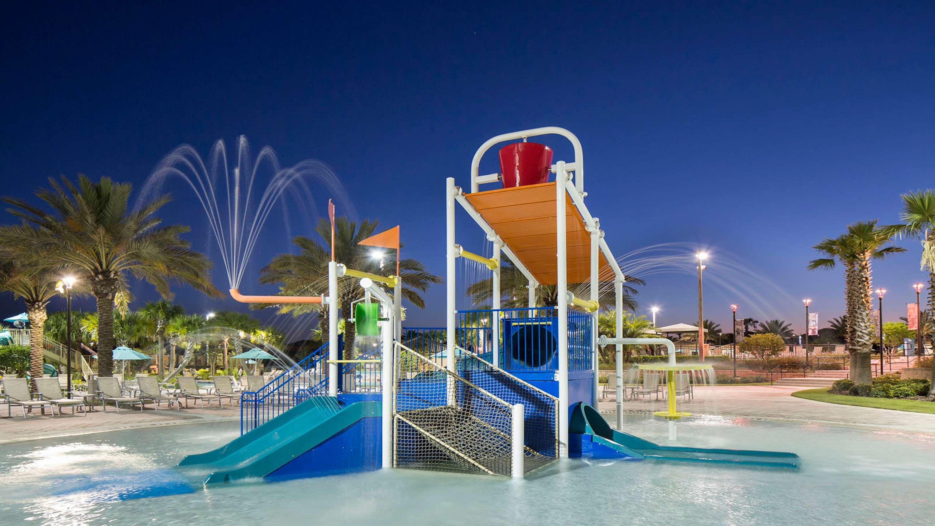 Ein Wasserpark mit Wasserrutsche, Schwimmbad und Palmen.