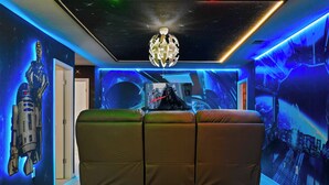 A room with a sofa, a ceiling light fixture, and a wall with a space-themed mural. - Fancy Game Theater 10br Villa W/pool/spa Disney (Davenport)