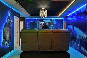 Une pièce comprenant un canapé, un luminaire au plafond et un mur orné d’une fresque sur le thème de l’espace.