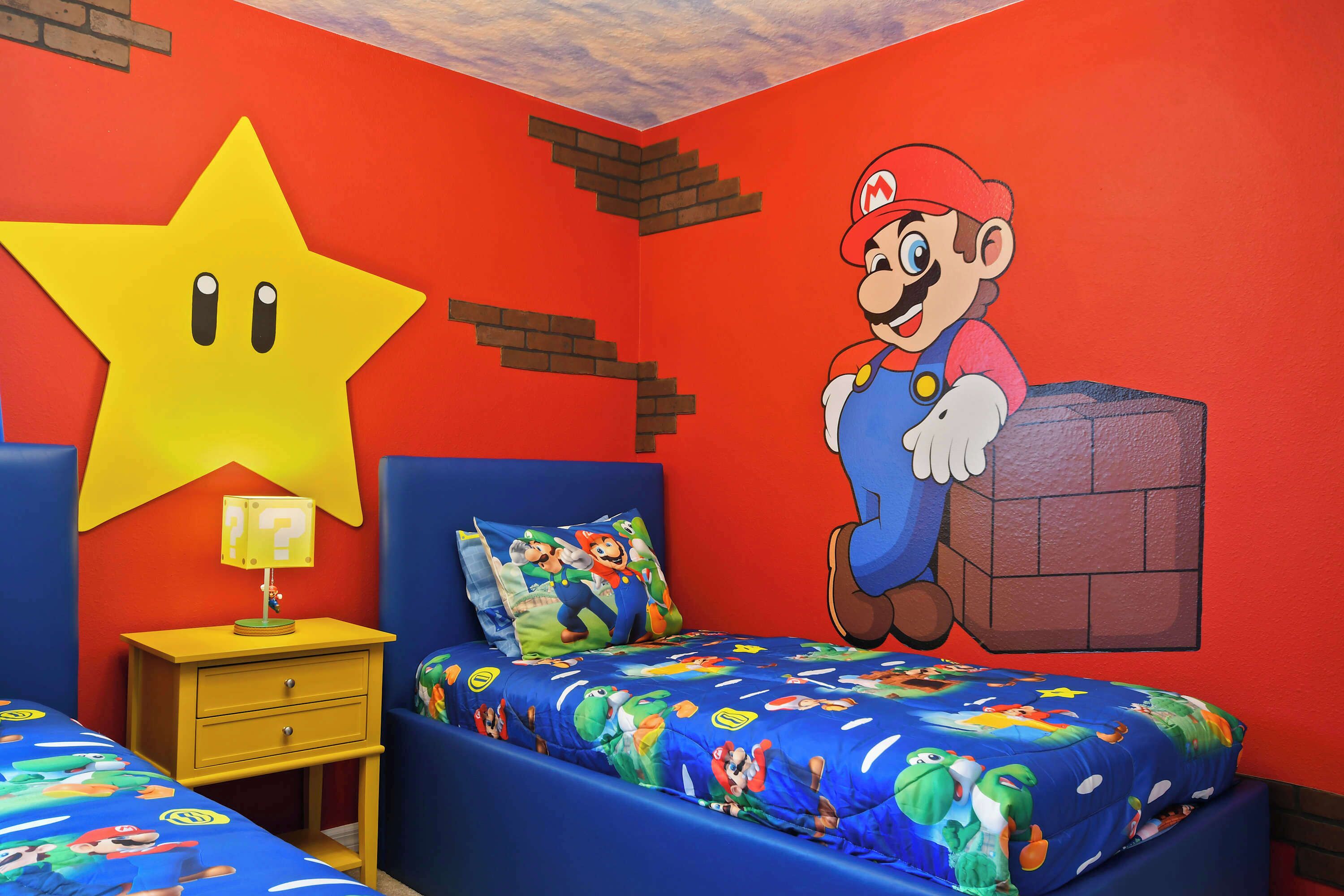 A bedroom with a Mario-themed bedspread, a large star decoration, and a Mario poster on the wall.
