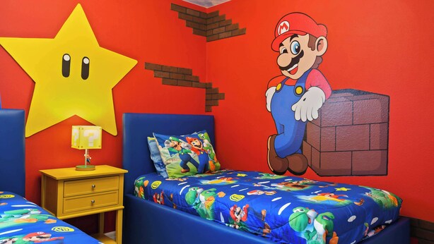A bedroom with a Mario-themed bedspread, a large star decoration, and a Mario poster on the wall. - Fancy Game Theater 10br Villa W/pool/spa Disney (Davenport)