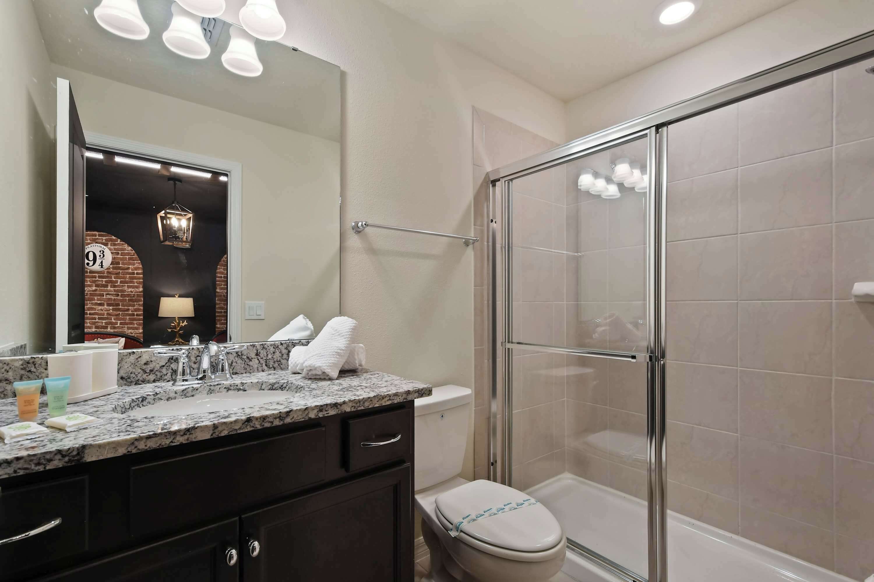 A bathroom with a shower, a toilet, a vanity with a mirror, and a sink.