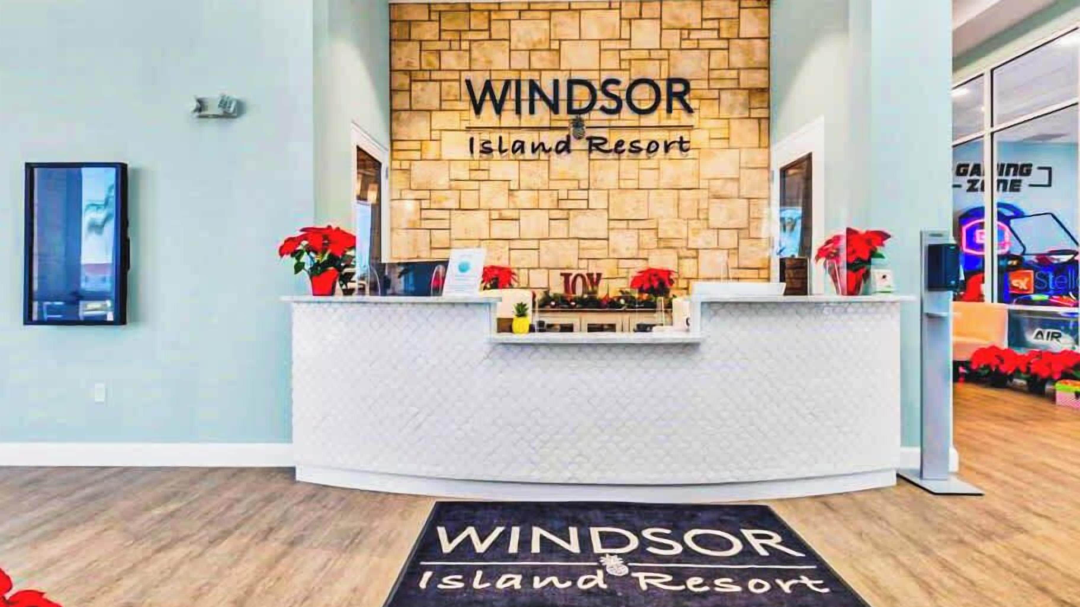A reception desk at Windsor Island Resort with a stone wall backdrop and a welcome mat.