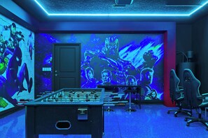 Une pièce avec une table de baby-foot, une porte et un mur orné d’une grande fresque murale sur le thème des super-héros.