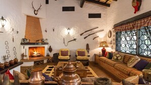 A rustic interior with a fireplace, seating, and various hunting and cooking utensils. - Sítio Dels Serrans - Jacareí (Jacarei)