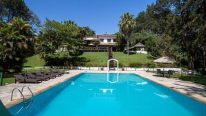 A swimming pool with a clear blue water, surrounded by lounge chairs and a small pavilion. - Sítio Dels Serrans - Jacareí (Jacarei)